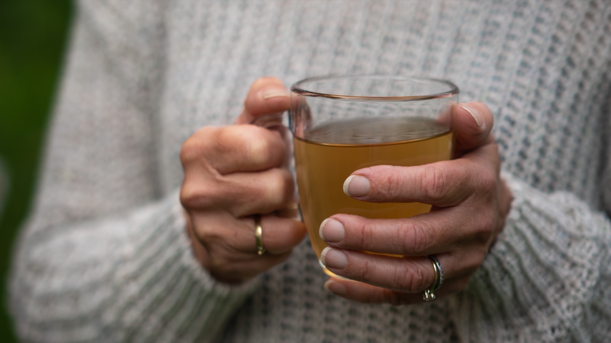 Twee handen om een glas thee in de tuin